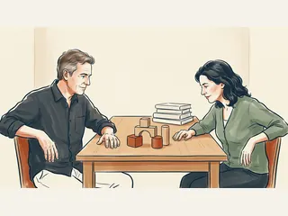 Dos adultos de piel clara observan piezas geométricas sobre una mesa.