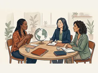 Tres mujeres conversan alrededor de una mesa con carpetas y un globo terráqueo sin fronteras.