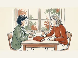Dos personas adultas conversan junto a una ventana con un libro cerrado sobre la mesa.
