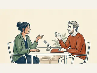 Dos personas adultas conversan ante un micrófono de mesa y una carpeta cerrada.