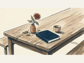 Una flor en un jarrón, un cuaderno cerrado y una pequeña pieza de cerámica sobre una mesa.