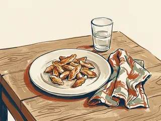 Un plato de tiras de pollo cocinado junto a una servilleta y un vaso.
