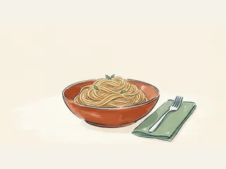 Cuenco color teja con fideos largos y pequeñas hojas verdes, junto a un tenedor sobre una servilleta.