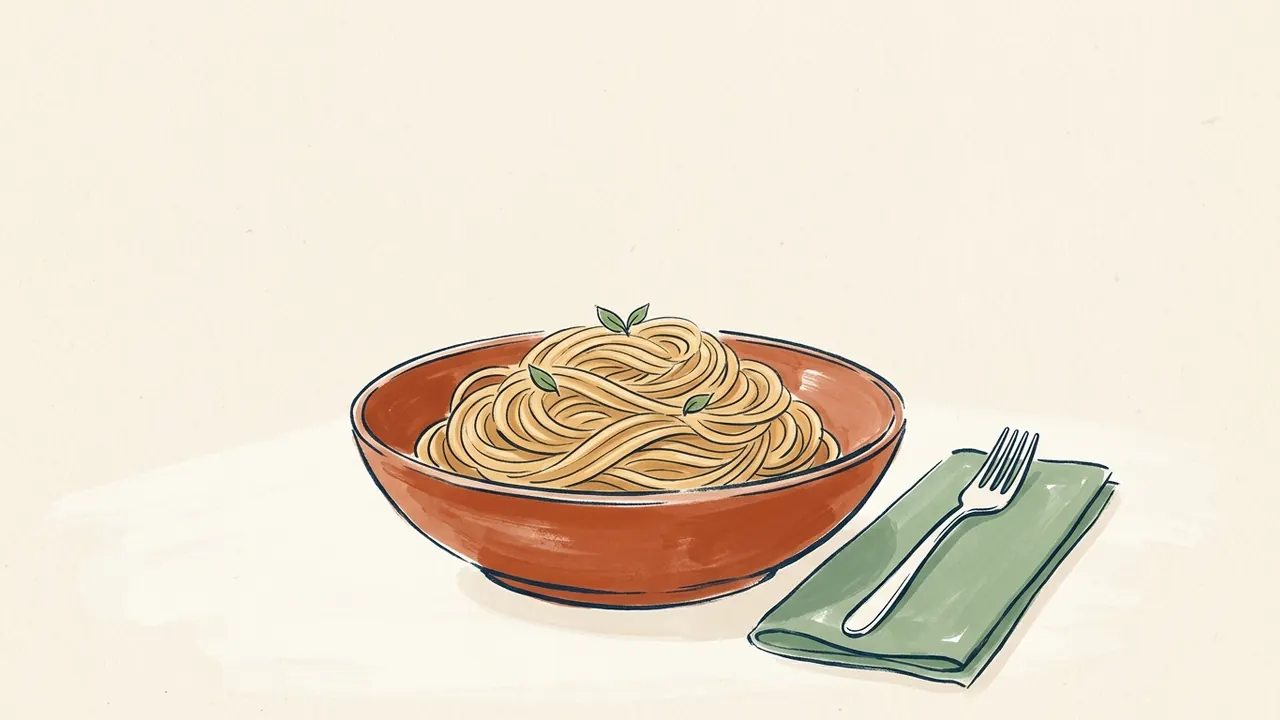 Cuenco color teja con fideos largos y pequeñas hojas verdes, junto a un tenedor sobre una servilleta.