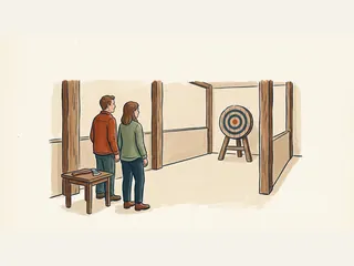 Dos personas observan una diana de madera; un hacha permanece sobre una mesa lateral.