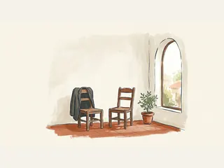 Dos sillas vacías junto a una ventana, una chaqueta en un respaldo y una planta.