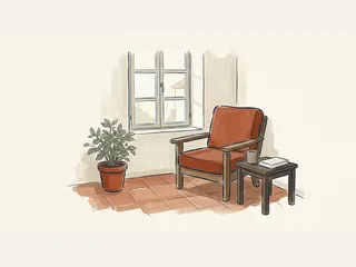 Rincón de lectura con una butaca vacía, un libro, una taza y una planta junto a una ventana.