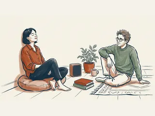 Dos personas sentadas junto a un altavoz, una planta y libros cerrados en una escena de escucha.