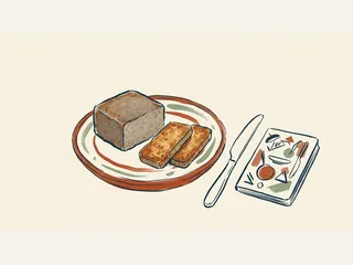 Un bloque rectangular de scrapple y dos lonchas doradas se presentan sobre un plato.