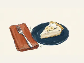 Porción de tarta de crema de plátano con dos rodajas y nata en un plato azul.